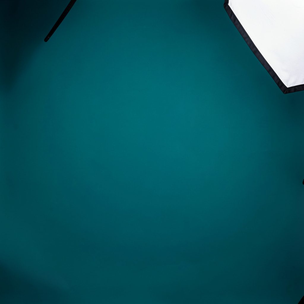 A wide aerial-style campus map illustration showing building blocks, pathways, and green spaces in muted teal, sage, and cream tones on a light background.