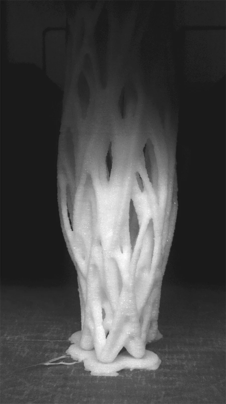Close-up of a woven, lattice-like white sculptural form with mesh-like interlacing strands, set against a dark background, conveying a calm, scholarly mood in muted neutrals
